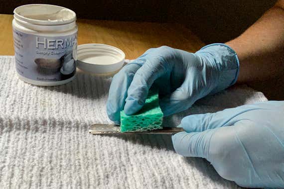  شخصی که با استفاده از اسفنج یک چنگال روکش نقره را صیقل می دهد 